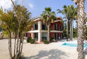 an exterior view of a house with palm trees and a swimming pool at Villa Nunziatina in Carlentini