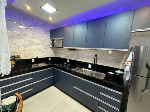 Apartamento no Centro de Nova Friburgo! في نوفا فريبورغو: مطبخ مع خزائن زرقاء وأجهزة حديد قابلة للصدأ