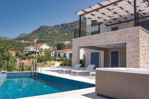a villa with a swimming pool with mountains in the background at Belsize Villas in Budva