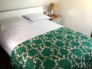 リングウッドにあるSelfcatering Coach House New Forest Dog Friendlyのベッド(緑と白の毛布付)