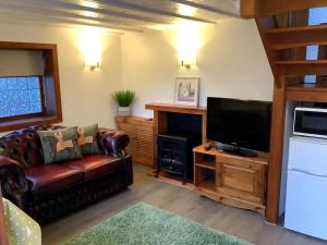 a living room with a couch and a flat screen tv at Selfcatering Coach House New Forest Dog Friendly in Ringwood