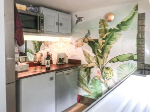 uma cozinha com um mural tropical na parede em Le Cabanon de Monte-Carlo avec Jardin Privé em Monte Carlo