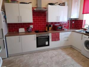 a kitchen with white cabinets and a washing machine at Nina's Cozy Lodge in Wigan