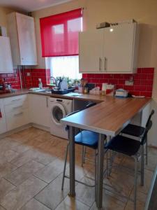 eine Küche mit einem Tisch und einer Waschmaschine in der Unterkunft Nina's Cozy Lodge in Wigan