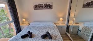 ein Schlafzimmer mit einem Bett mit Schuhen darauf in der Unterkunft Homes of Spain, Apartamentos Paraíso, Ed Palmerston, Atico O, Suite con Piscina Privada en solárium, vistas al mar, a 50 m de la playa, WIFI in Playas de Vera + 44 Fotos
