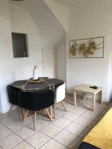 uma sala de estar com uma mesa e uma cadeira preta em Maison de ville em Le Petit-Quevilly