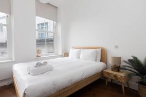 um quarto com uma cama com lençóis brancos e uma planta em Superb 1 Bedroom Apartment Holborn London em Londres