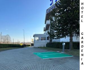 un estacionamiento con una señal verde para minusválidos frente a un edificio en Hotel Gardenia, en Romano Canavese