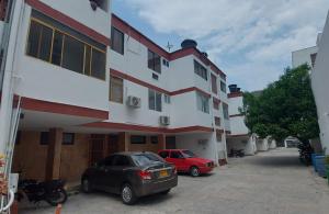 two cars parked in a parking lot next to a building at TOP SUITE Lugar encantador con parqueadero, internet 200Mgz in Santa Marta