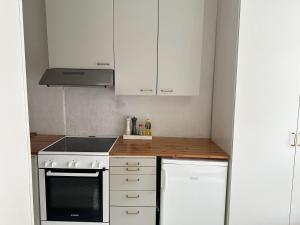 a kitchen with white cabinets and a stove top oven at Wooden house studio with shared garden in Helsinki