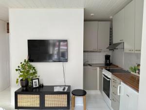 a kitchen with white cabinets and a tv on the wall at Wooden house studio with shared garden in Helsinki