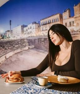 Eine Frau, die an einem Tisch mit einem Teller Essen sitzt. in der Unterkunft Il vecchio salone in Lecce