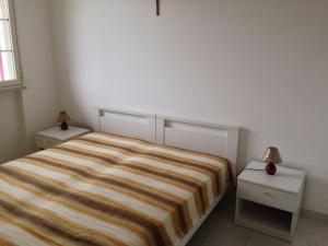 een slaapkamer met een gestreept bed en 2 nachtkastjes bij Leukos in Leuca