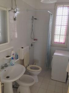 een witte badkamer met een toilet en een wastafel bij Leukos in Leuca