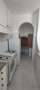 een witte keuken met een fornuis en een wastafel bij Leukos in Leuca