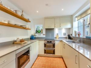 a kitchen with white cabinets and a counter top at Malting Cottage 