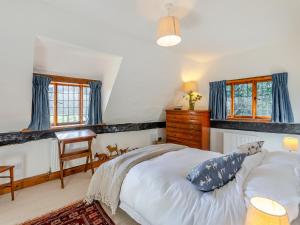 a bedroom with a bed and a desk and windows at Malting Cottage 