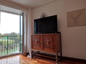 a television on a cabinet in a room with a window at Vive el puerto con párking privado GRATUITO!!! in Mundaka