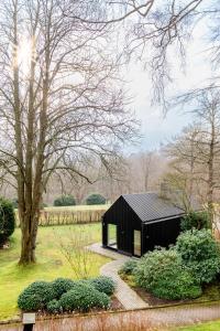 a black house in a garden with a tree at Aarskogs Boutique Hotel in Glücksburg