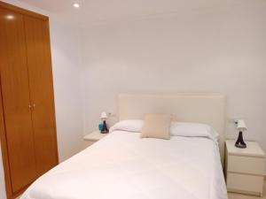 een slaapkamer met een wit bed en 2 nachtkastjes bij Apartamento Luna in Gandía