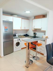 cocina con armarios blancos, mesa y lavavajillas en Apartamento Luna en Gandía