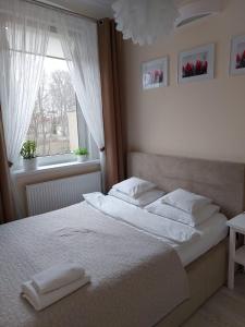 - une chambre avec un lit doté de draps blancs et une fenêtre dans l'établissement come&stay Zielona Góra, à Zielona Góra