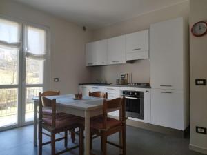 eine Küche mit weißen Schränken sowie einem Tisch und Stühlen in der Unterkunft La Tita in Somendenna