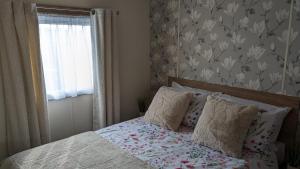 a bedroom with a bed with a flower patterned wall at Floppyfeet Pet Friendly Holiday Home Rental Thornwick Bay, Flamborough in Flamborough