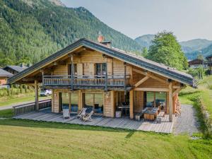 a log cabin with a deck and mountains in the background at Chalet Argentière, 6 pièces, 12 personnes - FR-1-343-181 in Chamonix