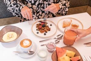 グロースアルルにあるHotel Nesslerhofのテーブルで皿に食べ物を盛り付けて食事をしている人
