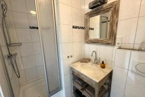 a bathroom with a sink and a shower with a mirror at Antares Spiekerooger Gästehaus-Sonnengartenbalkon West - Wohnung 6 in Spiekeroog