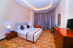 um quarto de hotel com uma cama e uma televisão em GREEN GARDEN HOTEL em Doha