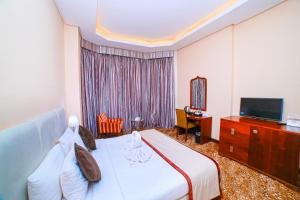 GREEN GARDEN HOTEL في الدوحة: غرفه فندقيه سرير وتلفزيون