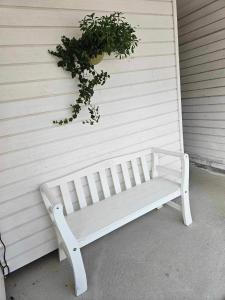 a white bench next to a wall with a plant at Toppleiligheit - Eidsgata 49 in Nordfjordeid