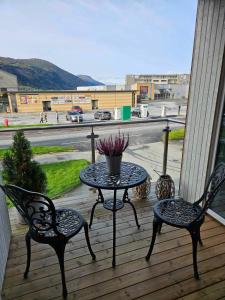 a table and chairs on a porch with a view of a street at Toppleiligheit - Eidsgata 49 in Nordfjordeid