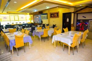 uma sala de jantar com mesas e cadeiras amarelas em GREEN GARDEN HOTEL em Doha