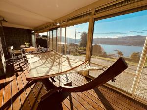 a rocking chair on a porch with a view of a lake at THERANCOBAY - lake view apartment - in Ranco
