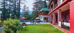 a building with a yard with chairs and tables and umbrellas at Valley View rooms near Khajjiar Lake in Lāhri