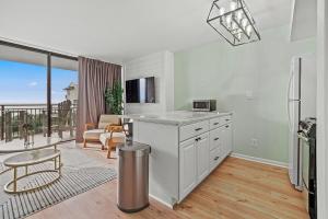 eine Küche mit weißen Geräten und ein Wohnzimmer mit einem Balkon in der Unterkunft Cabana Palms - Oceanfront Renovated King Bed Sauna in Myrtle Beach