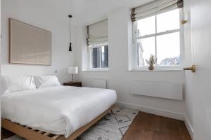 a white bedroom with a bed and a window at Splendid 2 Bedroom Duplex Holborn london in London