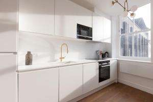 a white kitchen with white cabinets and a sink at Splendid 2 Bedroom Duplex Holborn london in London