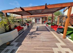 patio z czerwonymi kanapami i drewnianą pergolą w obiekcie Magnifique maison de vacances à paris w mieście Paray-Vieille-Poste