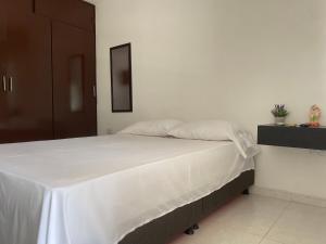 um quarto com uma cama com lençóis brancos em Apartamento moderno cerca al aeropuerto em Neiva