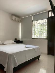 a white bedroom with a bed and a window at Apartamento moderno cerca al aeropuerto in Neiva
