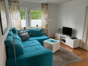 a living room with a blue couch and a tv at Apartment Oesterling in Wardenburg