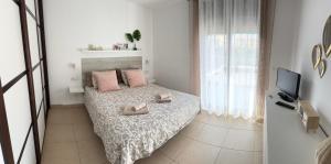 a bedroom with a bed with pink pillows and a tv at Cómodo apartamento en El Palm mar in Palm-Mar