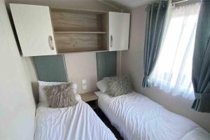 a room with two beds and a cabinet and a window at Scottish Holiday Home in Ardeer Square
