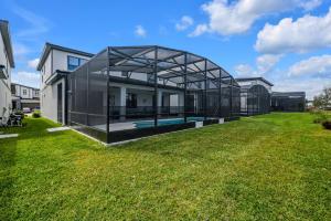 a glass house with a swimming pool in a yard at Orlando's Best Escape Residence at Paradiso Grande Resort home in Orlando