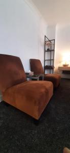 a living room with two brown chairs and a table at Luton Lodge - Near London Luton Airport Luxury Quite Rooms Close to Restaurants & Shops in Luton