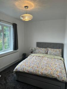 een slaapkamer met een bed en een kroonluchter bij Luton Lodge - Near London Luton Airport Luxury Quite Rooms Close to Restaurants & Shops in Luton